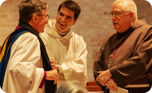 Three Clergymen of different faith traditions standing together talking and smiling.